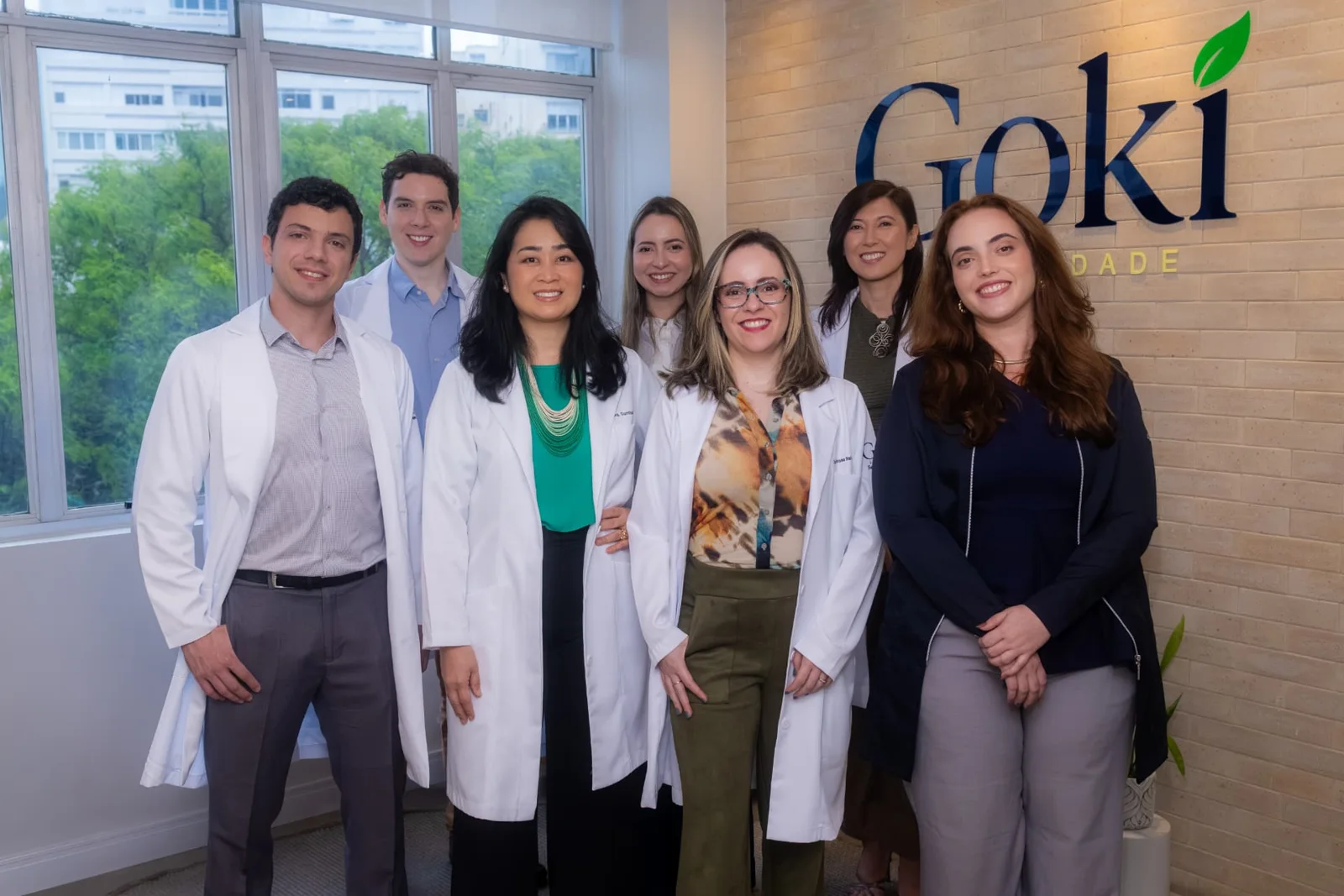 Equipe da Gokí Longevidade reunida no consultório, em frente ao logo da Gokí